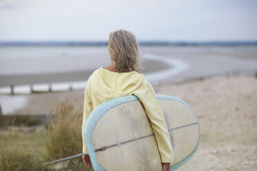 Ältere Frau geht zum Strand, trägt Surfbrett, Rückansicht - CUF30249