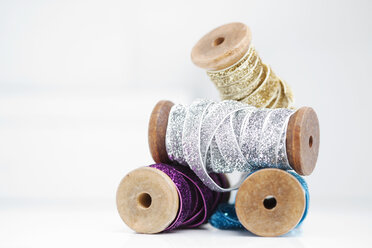 Stack of wooden reel with sparkly silver, gold, blue and purple ribbons - CUF30289