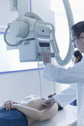 Röntgenassistentin bereitet sich auf die Röntgenaufnahme eines männlichen Patienten vor - ISF09578