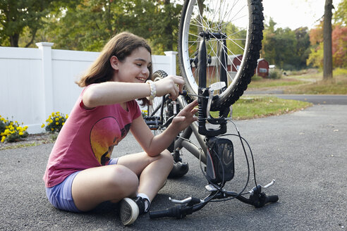 Mädchen repariert Fahrrad in der Einfahrt - ISF09593