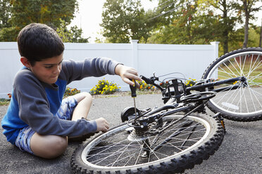 Entschlossener Junge repariert Fahrrad in der Einfahrt - ISF09594