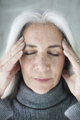 Close up of mature woman meditating with eyes closed and hands on forehead - ISF09622