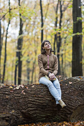 Mädchen träumt auf einem Baumstamm im Herbstwald - CUF30520