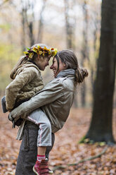 Mother carrying daughter in autumn forest - CUF30523