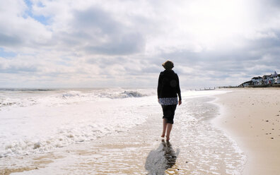 Ältere Frau, die am Strand entlang geht, Rückansicht - CUF30536