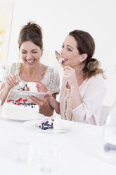 Mature woman eating cake, licking cake server smiling - CUF30571