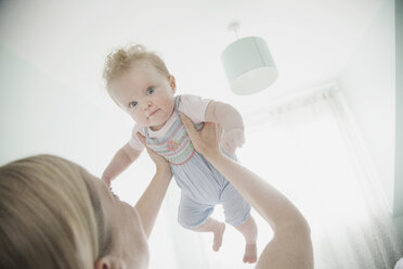 Mother holding baby daughter in air - CUF30647