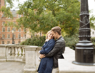 Young couple hugging outside Albert Hall, London, England, UK - CUF30773