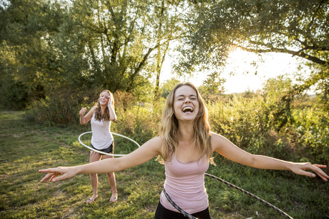 Zwei junge Mädchen in ländlicher Umgebung, die mit Hula-Hoop-Reifen herumalbern,, lizenzfreies Stockfoto