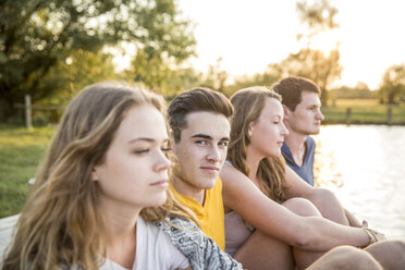 Group of friends sitting by lake, relaxing - CUF30846