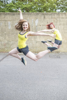 Junge Frauen springen vor einer Betonwand - CUF30876