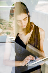 Young woman using digital tablet, photographed through glass - CUF31109