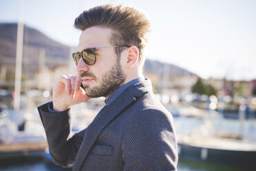 Cool young man talking on smartphone in harbor - CUF31140