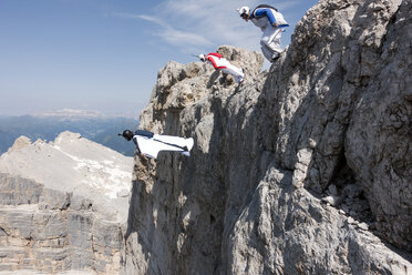 Drei männliche BASE-Springer beim Absprung von einem Berggipfel, Dolomiten, Italien - CUF31201