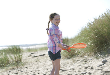 Seitenansicht eines Mädchens, das einen orangefarbenen Sportschläger hält und lächelnd in die Kamera schaut - CUF31208