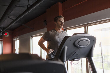 Erschöpfter Mann im mittleren Erwachsenenalter läuft auf dem Laufband im Fitnessstudio - ISF09649