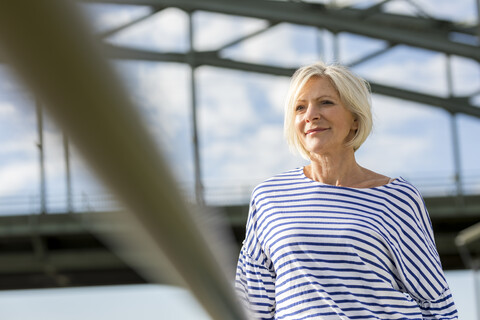 Porträt einer lächelnden älteren Frau an einer Brücke, lizenzfreies Stockfoto