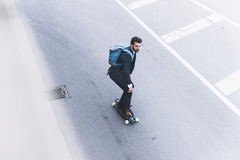 Geschäftsmann fährt Skateboard auf der Straße - UUF14086