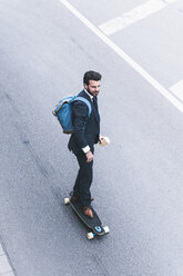 Geschäftsmann fährt Skateboard auf der Straße - UUF14087