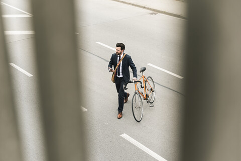 Geschäftsmann mit Fahrrad und Mobiltelefon auf der Straße, lizenzfreies Stockfoto