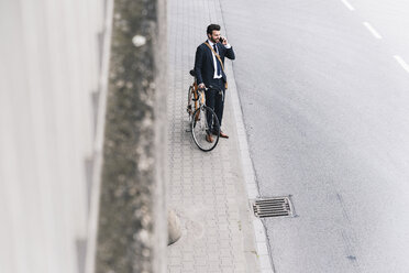 Businessman with bicycle on cell phone at the street - UUF14097