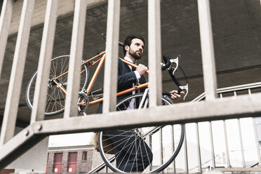 Businessman carrying bicycle at the station - UUF14098