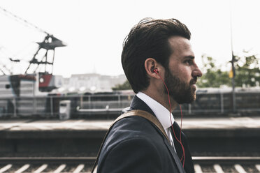 Businessman with earphones waiting at the platform - UUF14110
