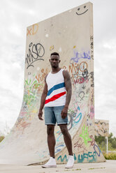 Young man in skatepark standing in front of graffiti - ACPF00002