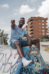 Young man in skatepark sitting on wall, laughing - ACPF00014