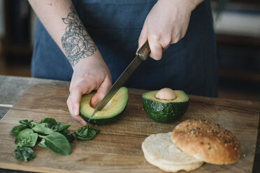 Woman preparing vegan burger, slicing avocado - ALBF00391