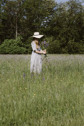 Italy, Veneto, Young woman plucking flowers and herbs in field - ALBF00403