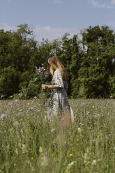Italien, Venetien, Junge Frau pflückt Blumen und Kräuter auf einem Feld - ALBF00407