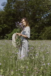 Italy, Veneto, Young woman plucking flowers and herbs in field - ALBF00408