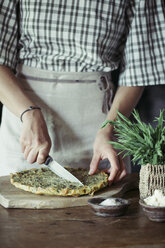 Young woman slicing homemade chickpea and herb cake - ALBF00423