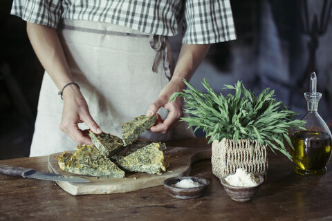 Junge Frau beim Garnieren von hausgemachtem Kichererbsen-Kräuterkuchen, lizenzfreies Stockfoto