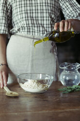 Young woman in kitchen preparing dough for fresh chickpea cake - ALBF00444