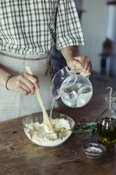 Young woman in kitchen preparing dough for fresh chickpea cake - ALBF00446