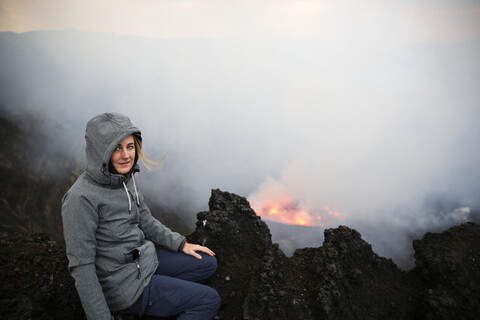 Afrika, Demokratische Republik Kongo, Virunga-Nationalpark, Frau sitzt über dem Nyiragongo-Vulkankrater, lizenzfreies Stockfoto