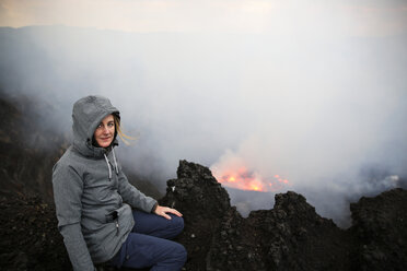 Afrika, Demokratische Republik Kongo, Virunga-Nationalpark, Frau sitzt über dem Nyiragongo-Vulkankrater - REAF00305