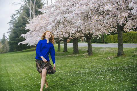 Young woman dancing barefoot in spring park stock photo