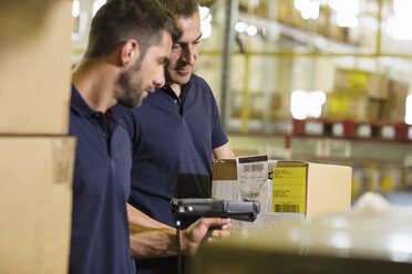 Male warehouse workers using barcode scanner in distribution warehouse - CUF31386