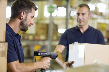 Two warehouse workers using barcode scanner in distribution warehouse - CUF31387