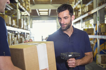 Warehouse worker using barcode scanner on cardboard box in distribution warehouse - CUF31389