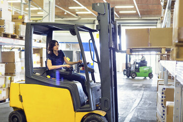 Female forklift truck driver working in distribution warehouse - CUF31392