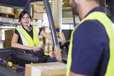 Supervisor instructing female forklift truck driver in distribution warehouse - CUF31393