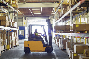 Silhouetted forklift truck at work in distribution warehouse - CUF31394