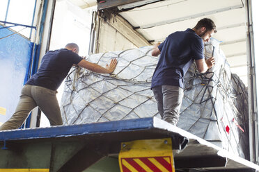 Workers pushing freight into air freight container - CUF31419