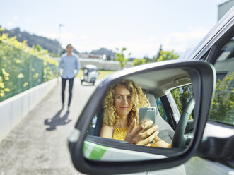 Smiling young woman using cell phone in electric car - CVF00800