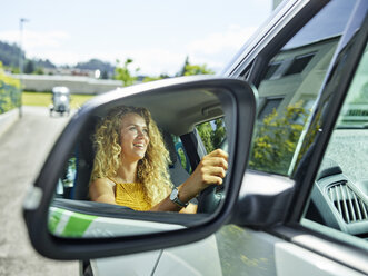 Spiegelung im Außenspiegel einer lächelnden Frau, die ein Elektroauto fährt - CVF00801