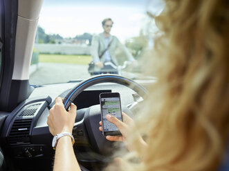 Young woman in electric car texting on cell phone - CVF00802